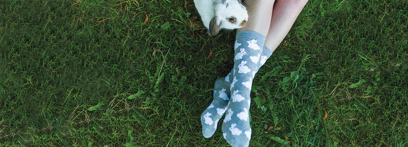 Cute fuzzy bunny socks for animal lovers from Wheel House Designs, styled on a model lounging in grass, showcasing the adorable bunny design.